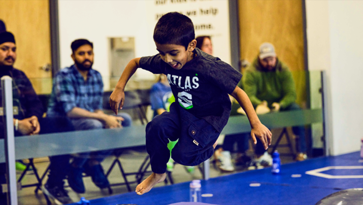 A cheerful KidStrong student high-fiving an encouraging KidStrong coach with smiles of accomplishment.